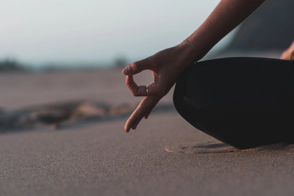 Mão em mudra sobre o joelho, numa meditação junto ao mar