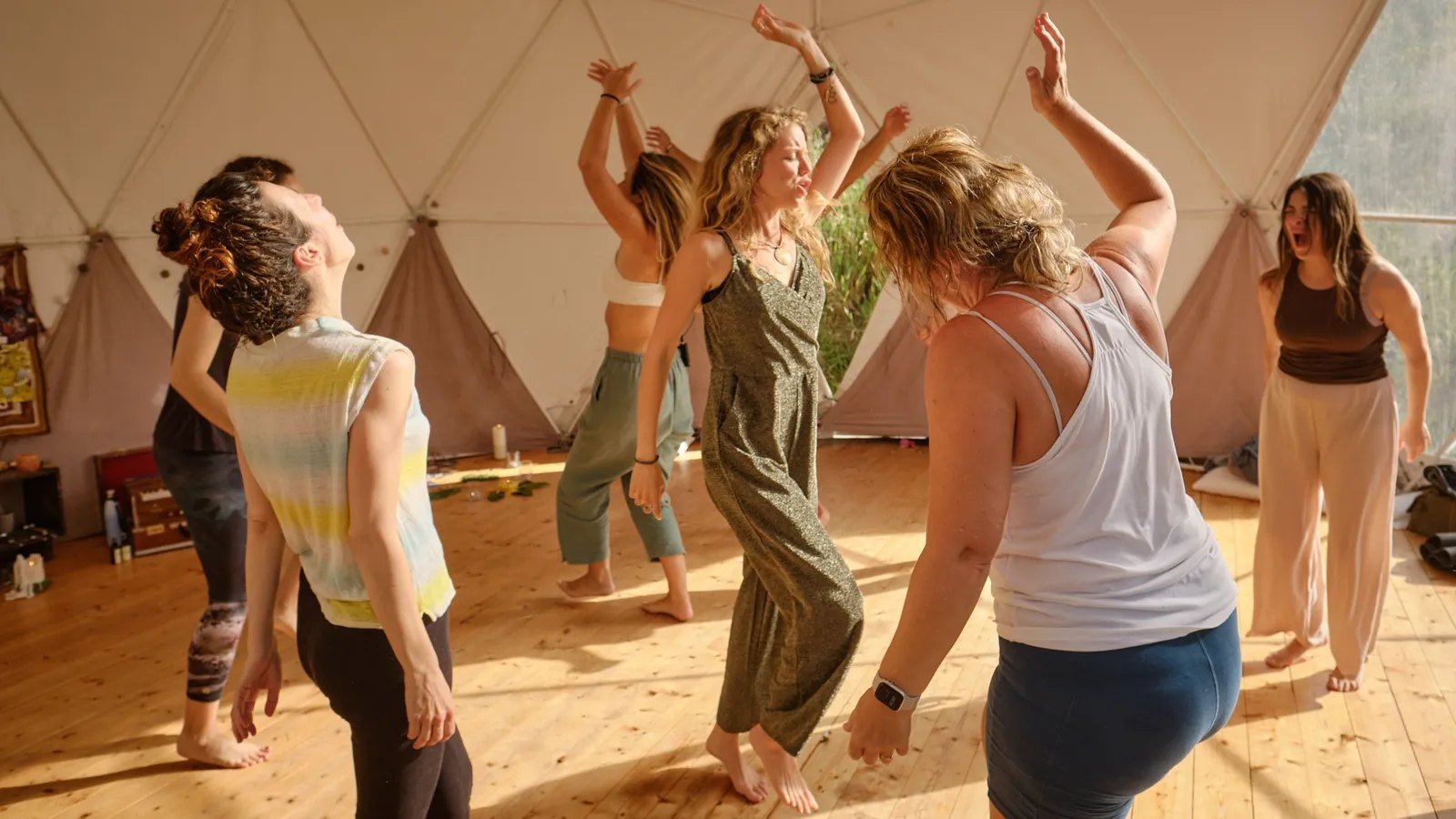 Grupo a dançar de braços no ar numa sessão Soma Groove, num domo de madeira